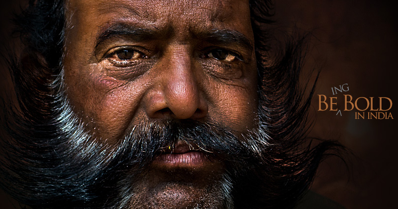 A portrait of a man with salt and pepper moustache on black background, and the text: Being bold in India