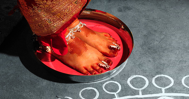 Una neosposa immerge i piedi nudi decorati in un liquido rosso