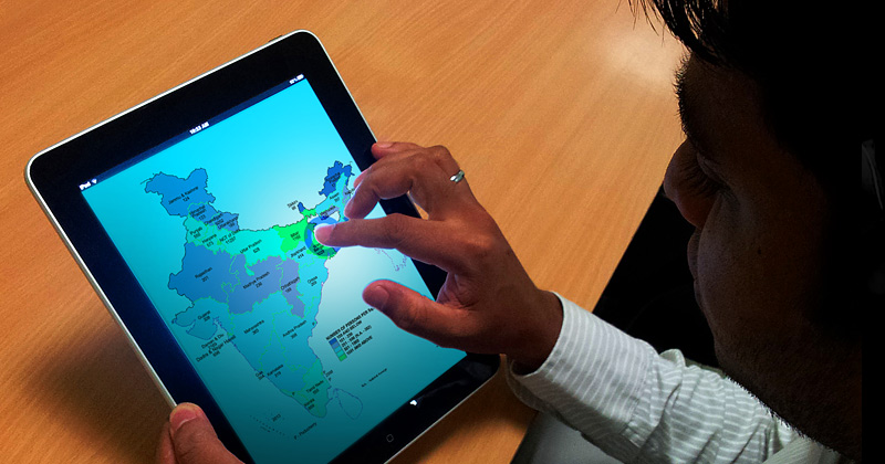 Ragazzo indiano con in mano  un tablet, sulla videata una mappa dell\\\'India