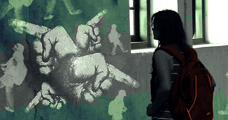 una donna, sacco in splalla, osserva i graffiti di mani che indicano tante direzioni, su un muro all'interno di un edificio